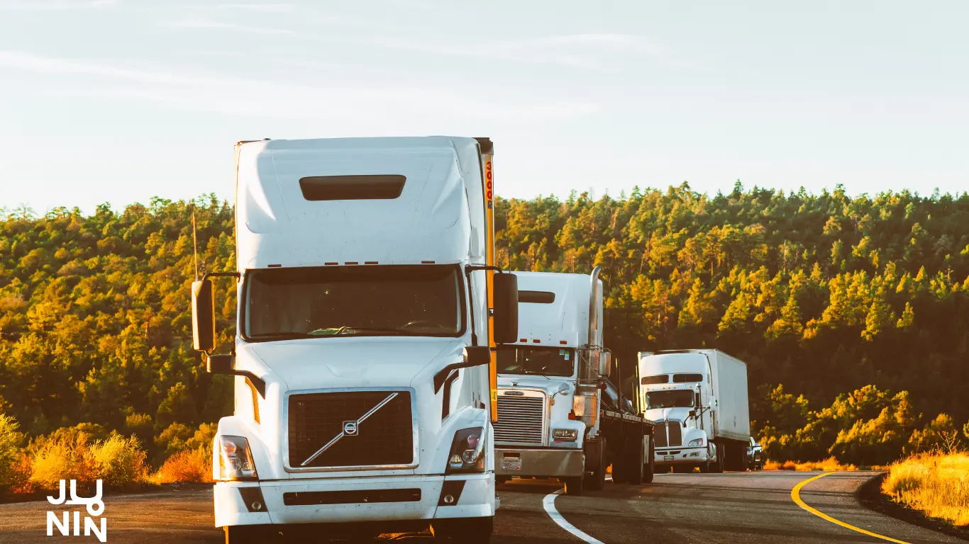 Se ve lo que parece un atardecer en la ruta, con una seguidilla de 3 camiones blancos que vienen circulando de frente al espectador.